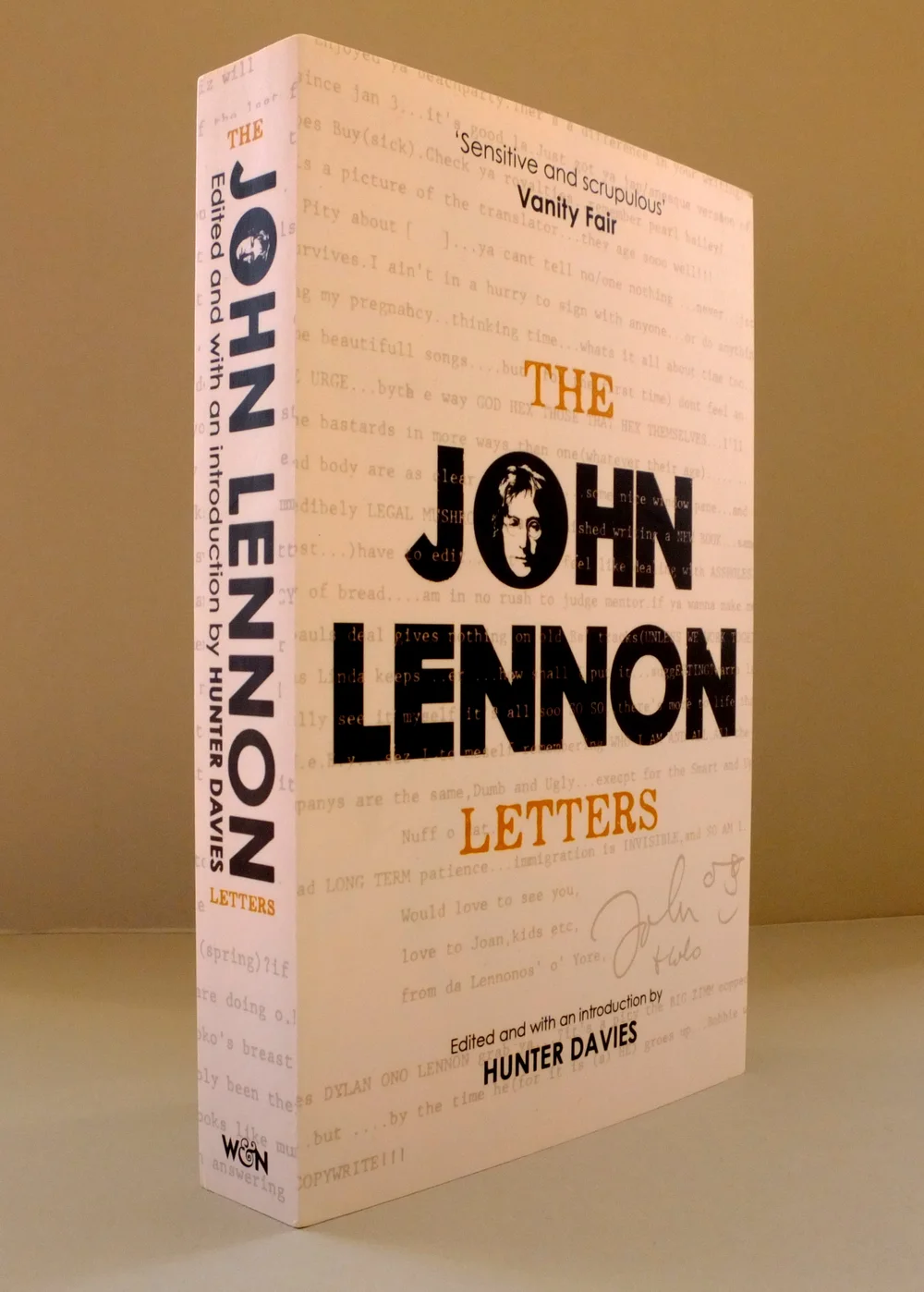 Paperback of The John Lennon Letters standing upright, typewritten letters printed faintly across the cream cover